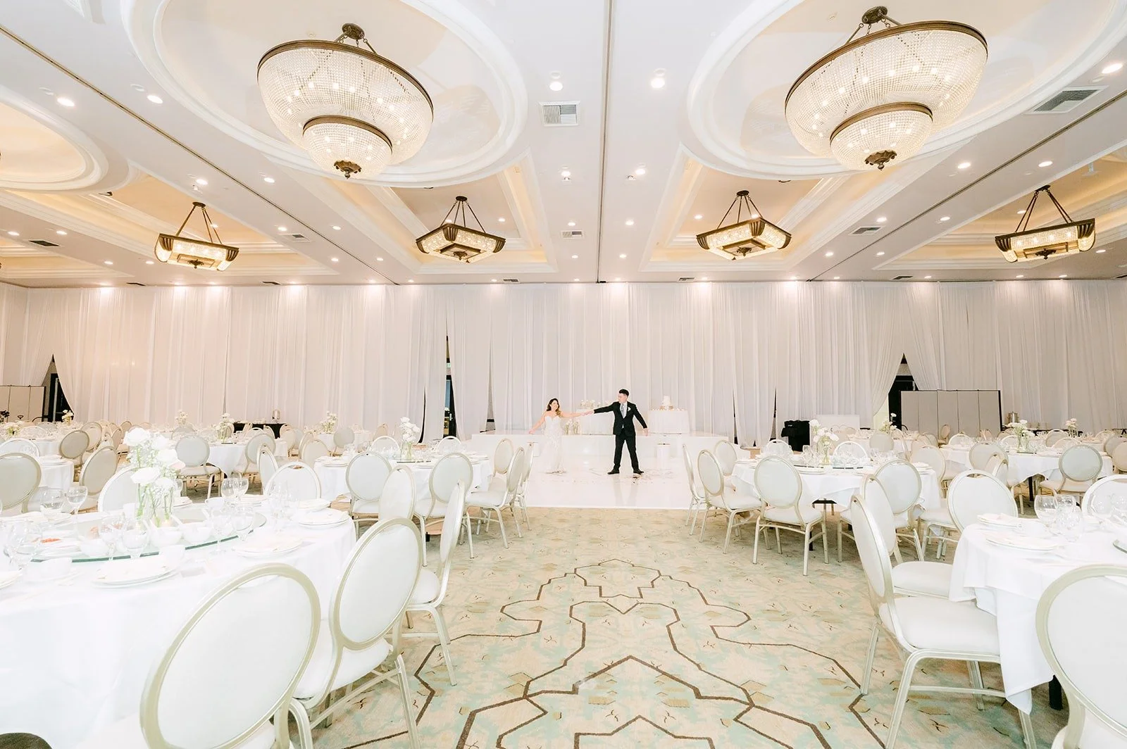 Wide view of the ballroom with chandeliers and white florals