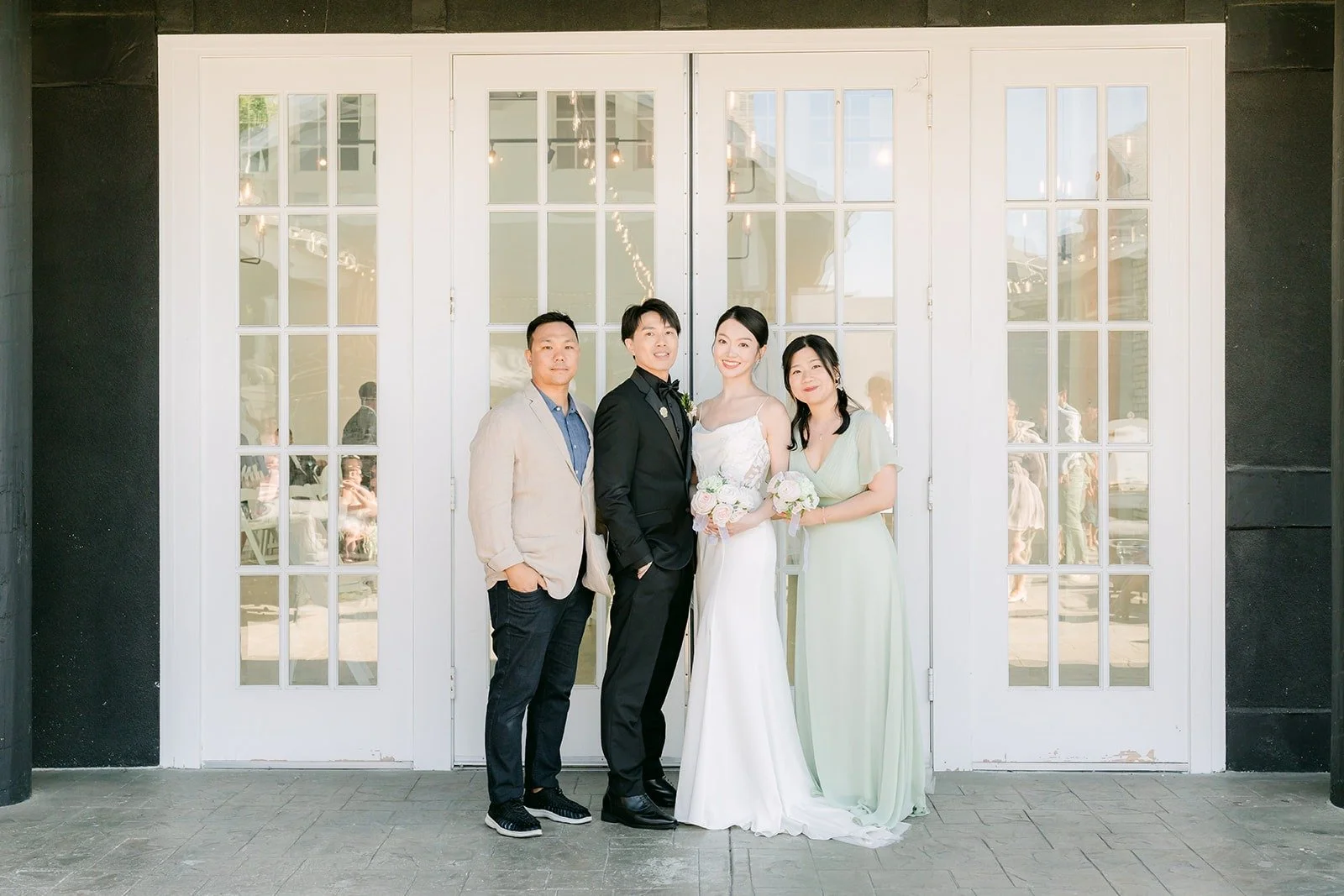 Tin and Fong with family in front of the white window panels on the cocktail patio, photographed by One and Only Production