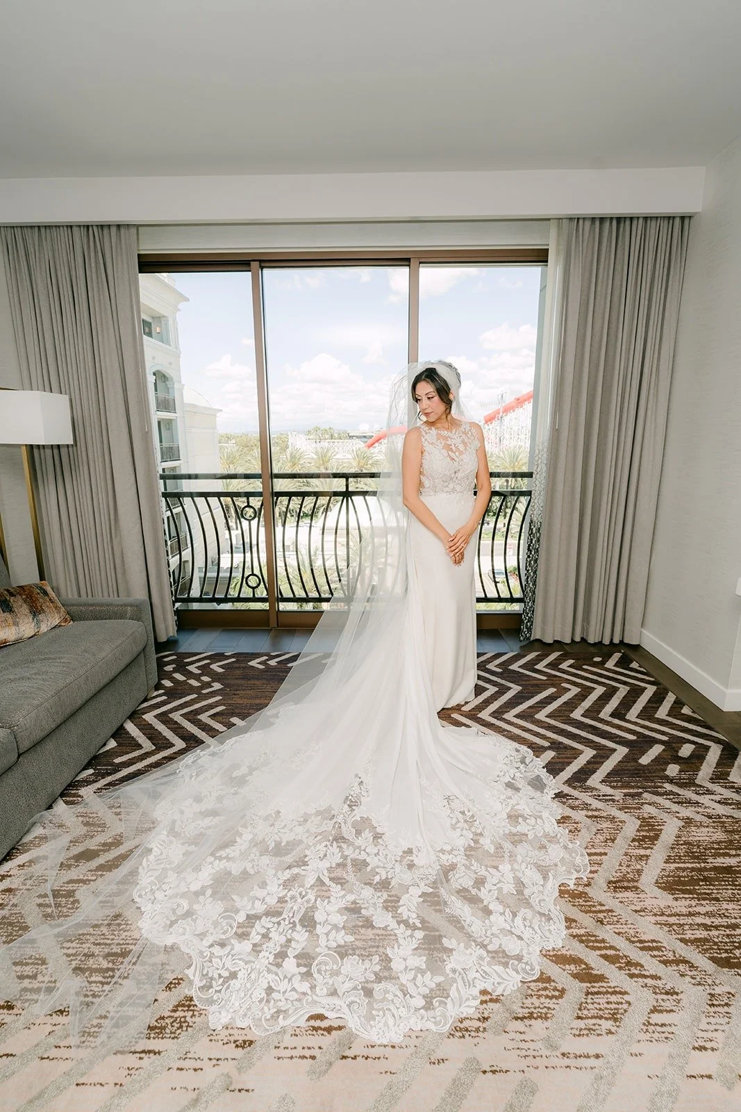 Francesca stands at the window in her gown and cathedral veil