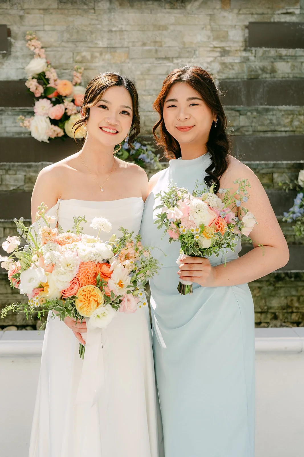 Amanda with a bridesmaid, both holding their bouquets.