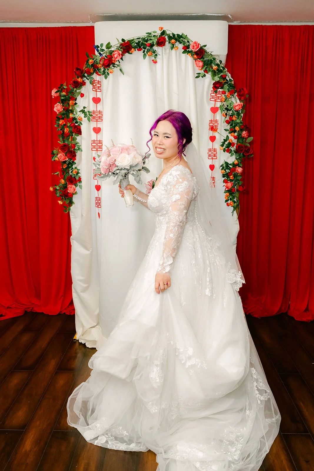 Vanessa smelling her bouquet with her train behind her.
