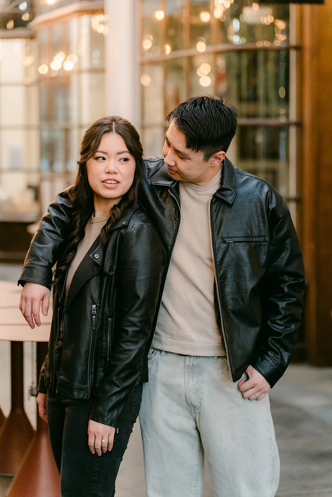 Emily leans into James's arms near the arcade storefronts.