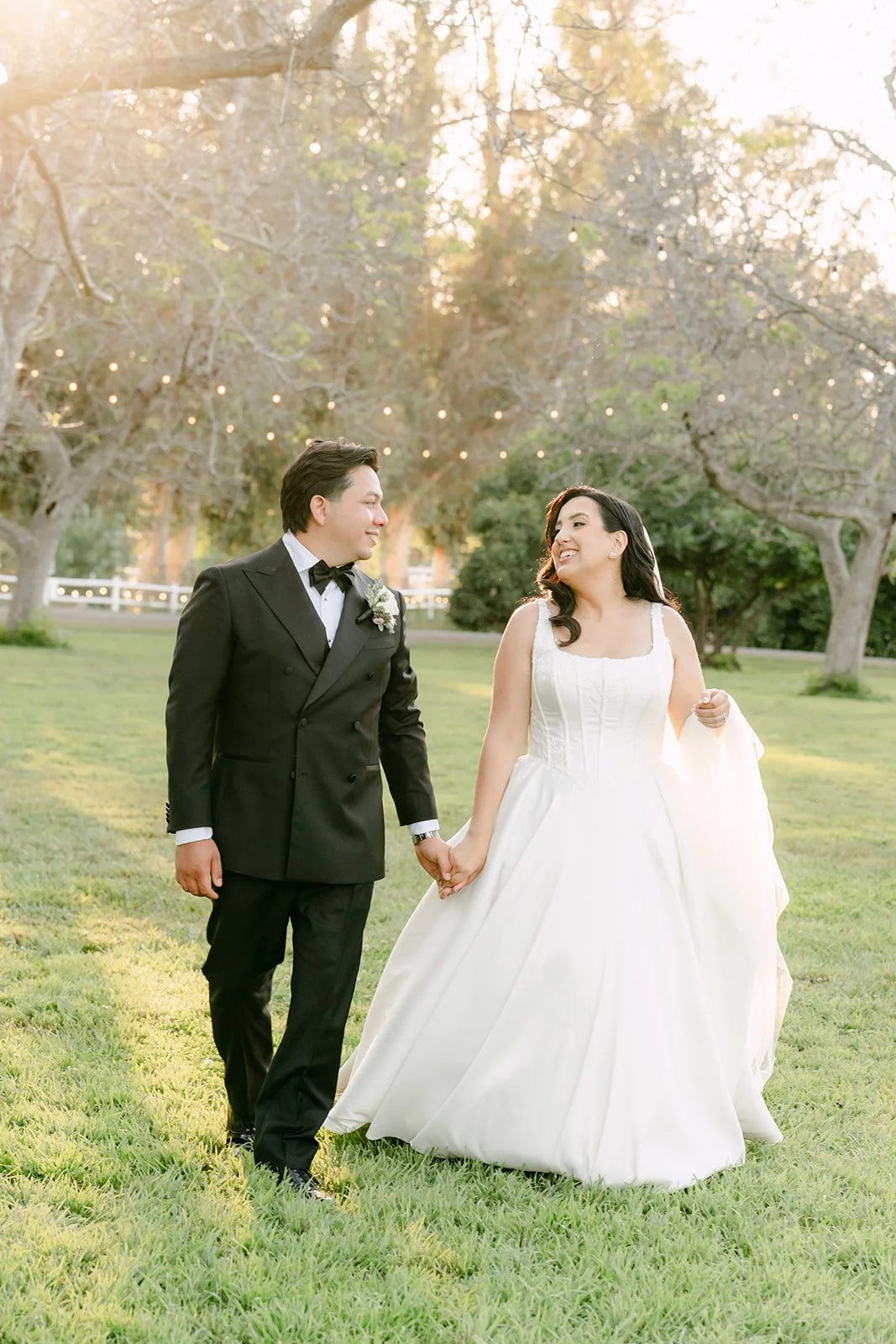 Couple walking hand in hand across the lawn at golden hour