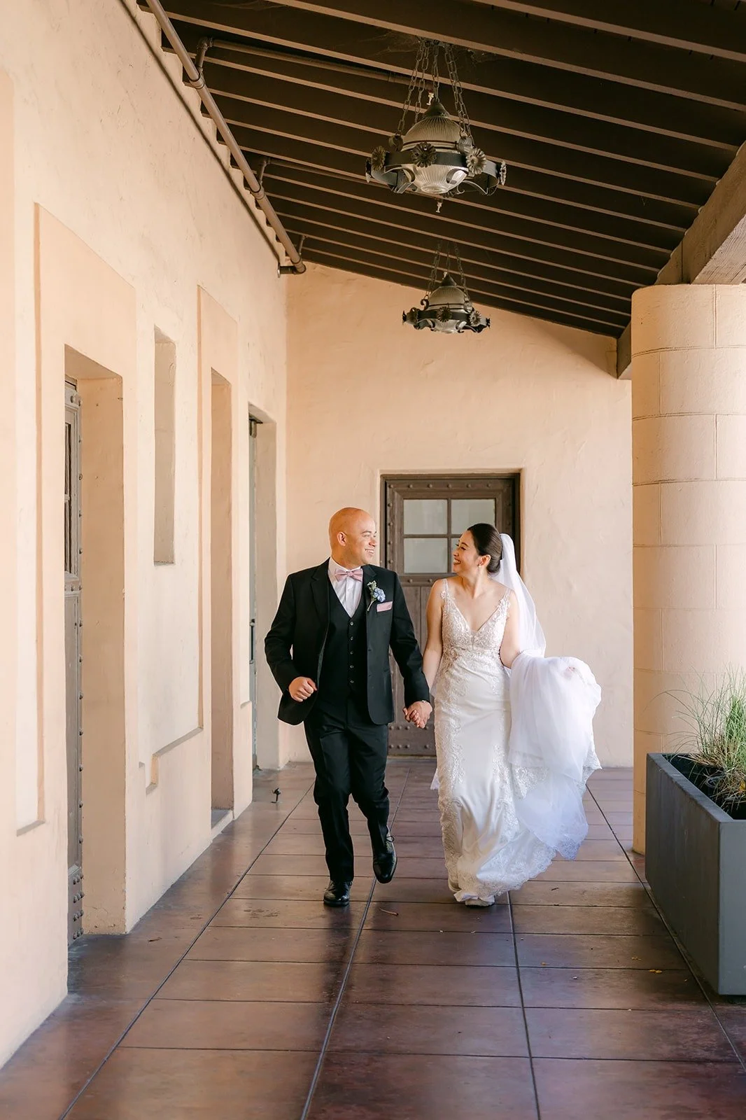 Elisa and Brandon walk hand in hand down the covered walkway