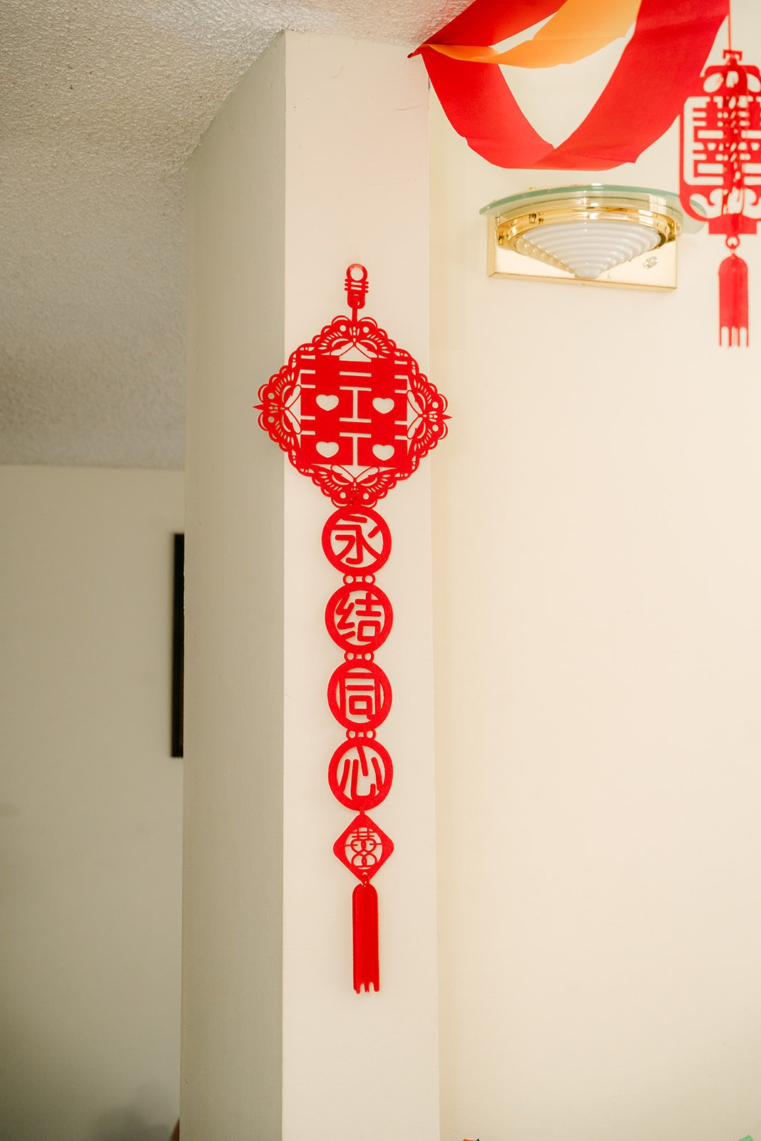 A red knot ornament hanging by the window.