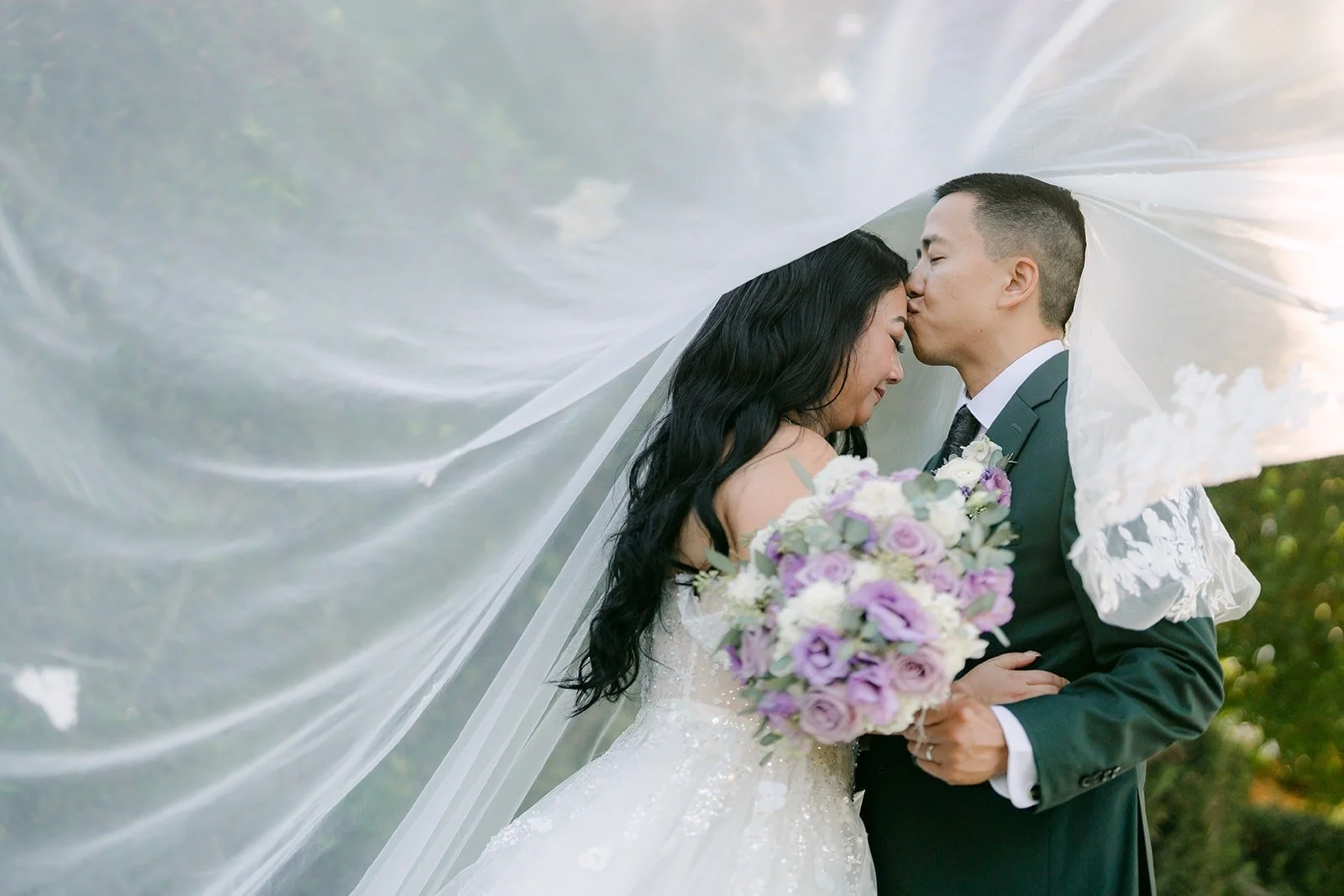 Kevin kisses Jennifer's forehead under her floating veil