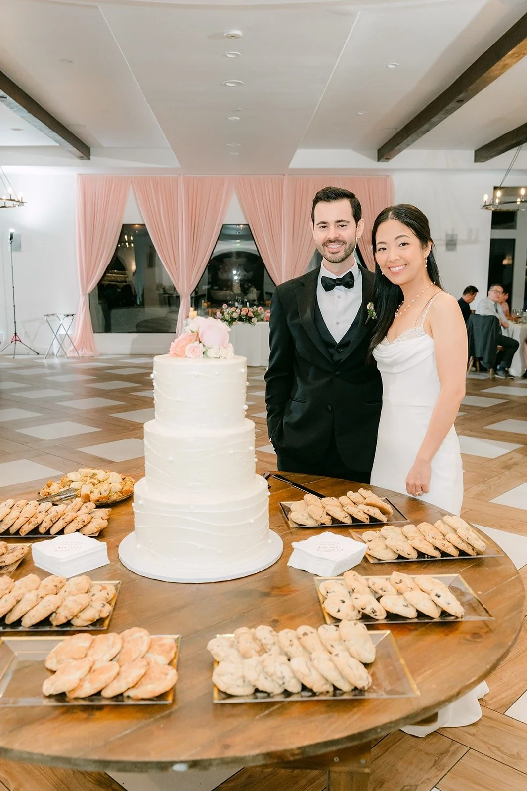 Stephanie and Kevin beside their cake on a wood table with desserts