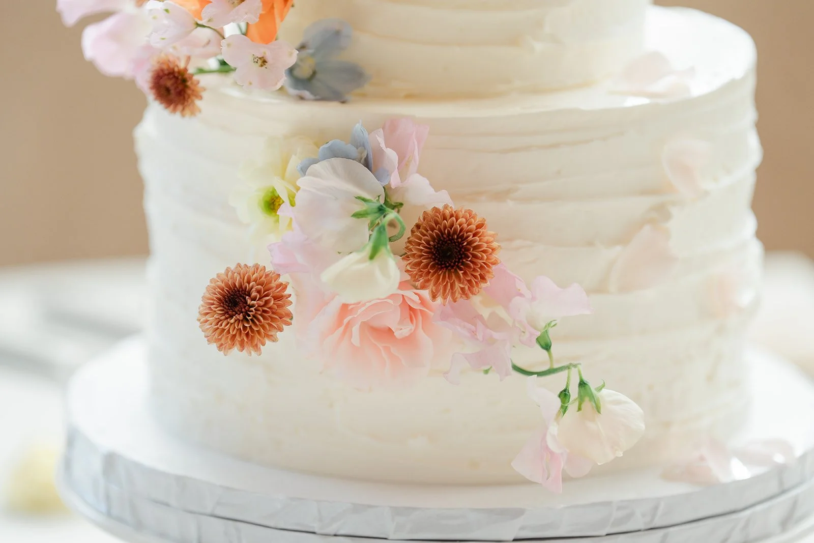Close up of the white wedding cake with pastel sugar flowers