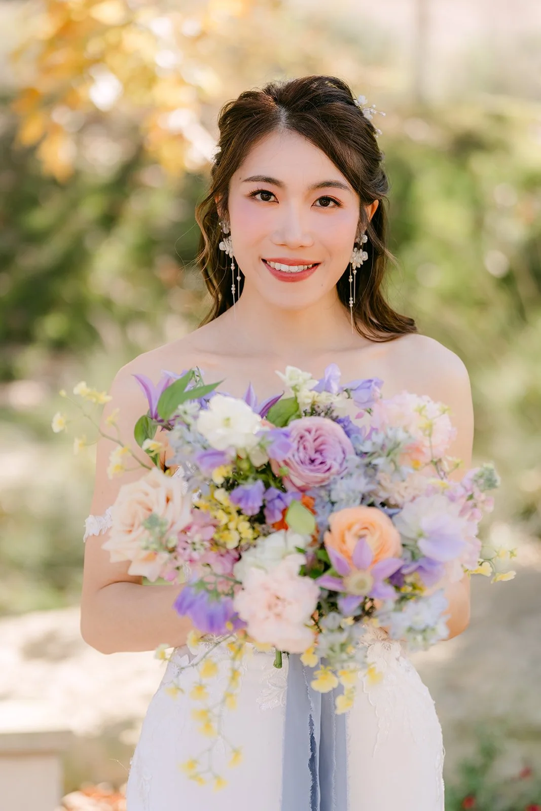 Christie smiling with her pastel bouquet in the afternoon light.