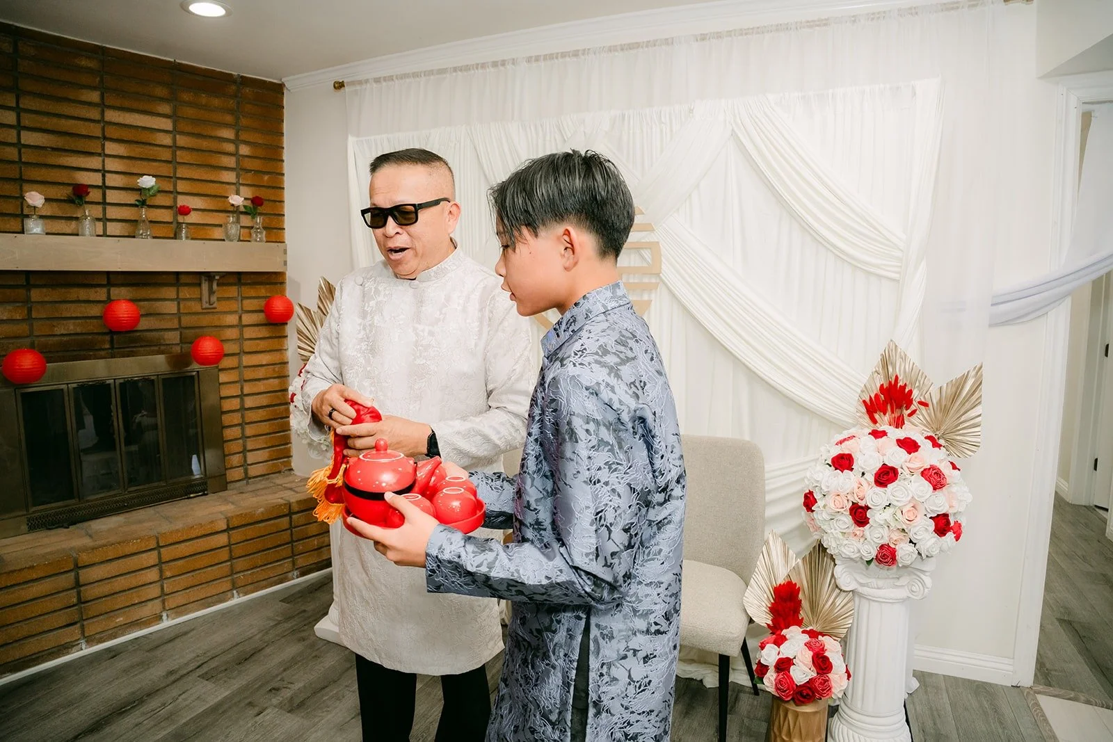 A family member in a white ao dai receives a red gift tray at the door