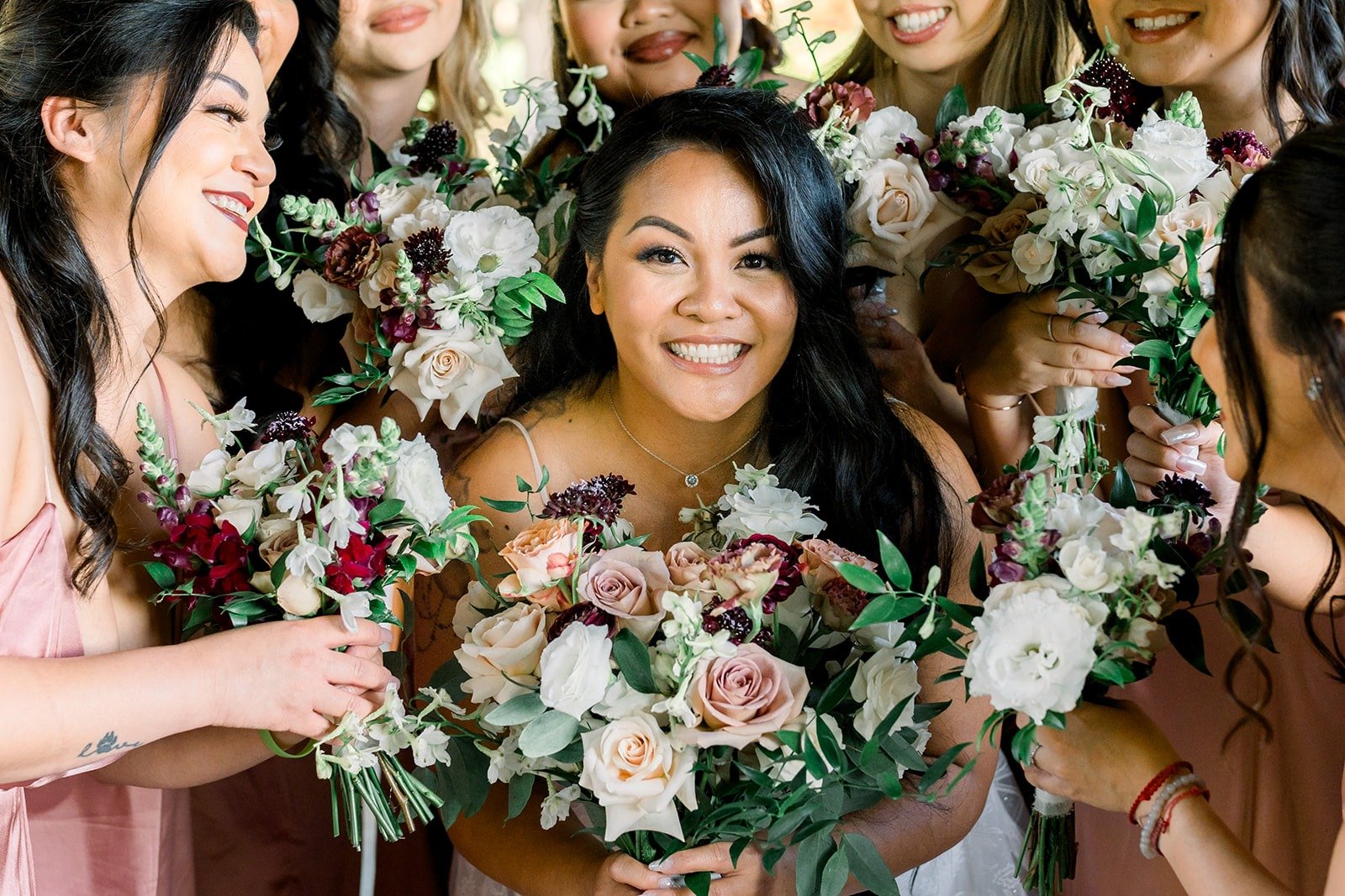 Betsy beams surrounded by her bridesmaids' bouquets