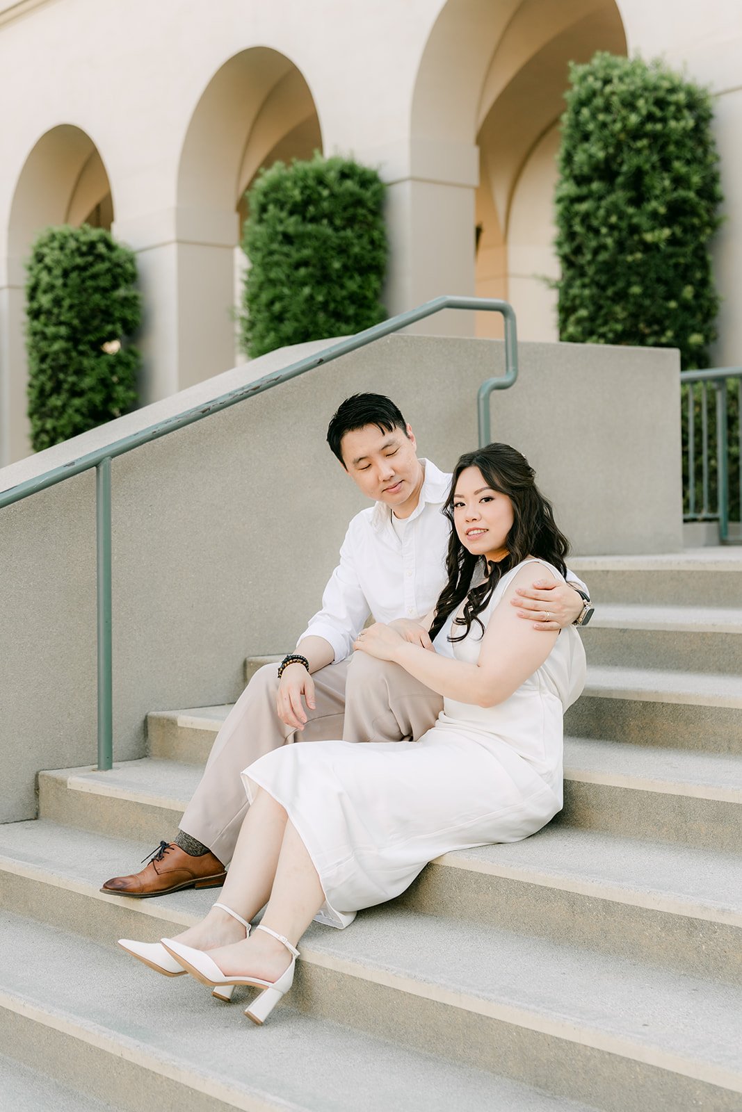 Emily and James sit together on the stone steps beneath the arches.