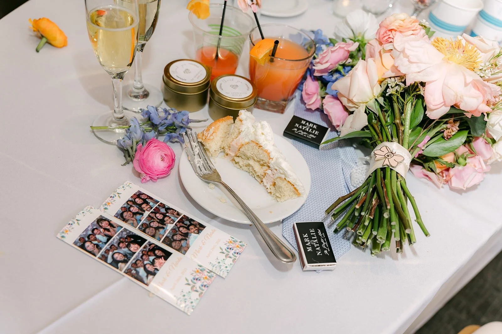 Drinks, photo booth strips and bouquets on a table during the reception