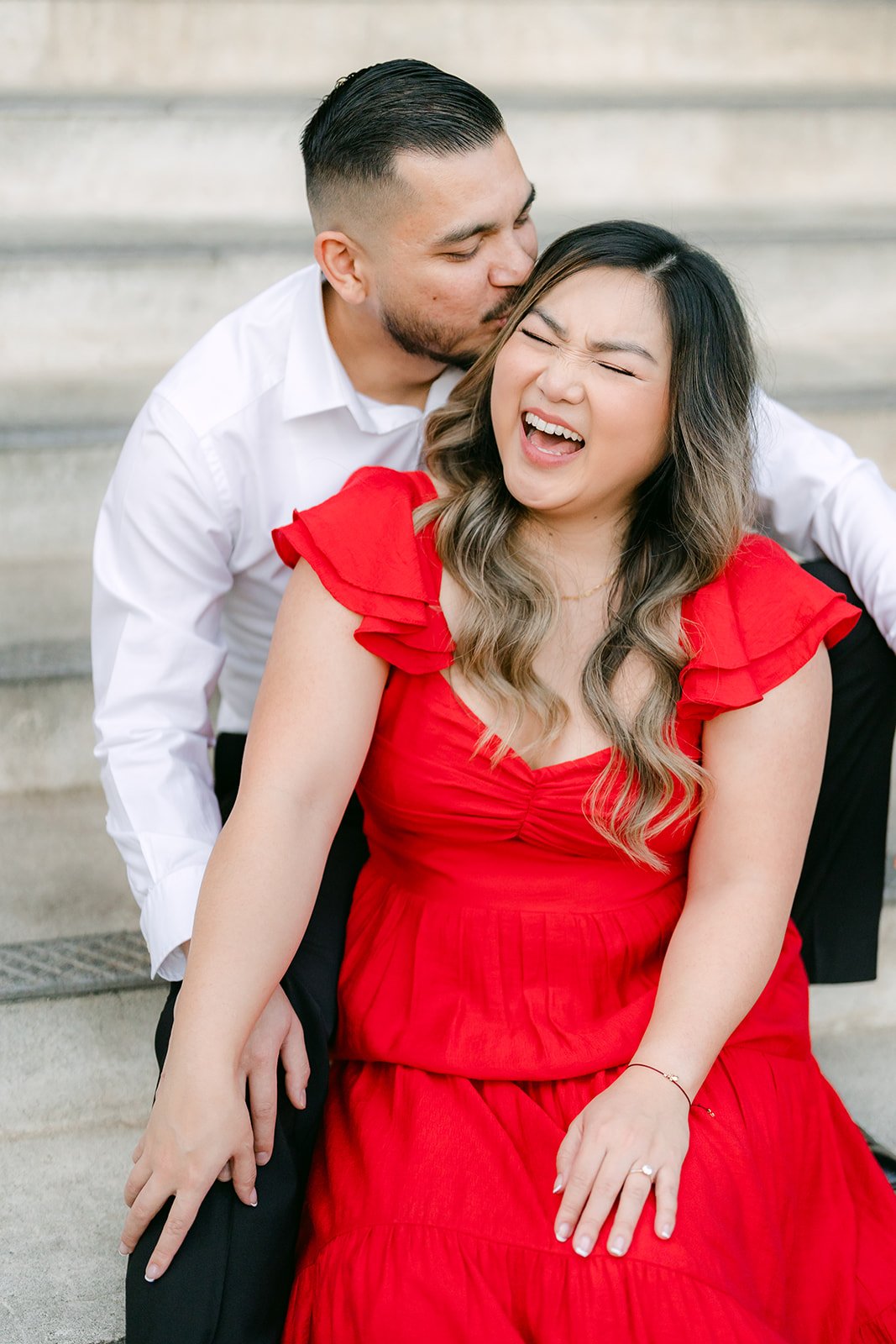 Ankush kisses Linh's cheek as she laughs on the steps.