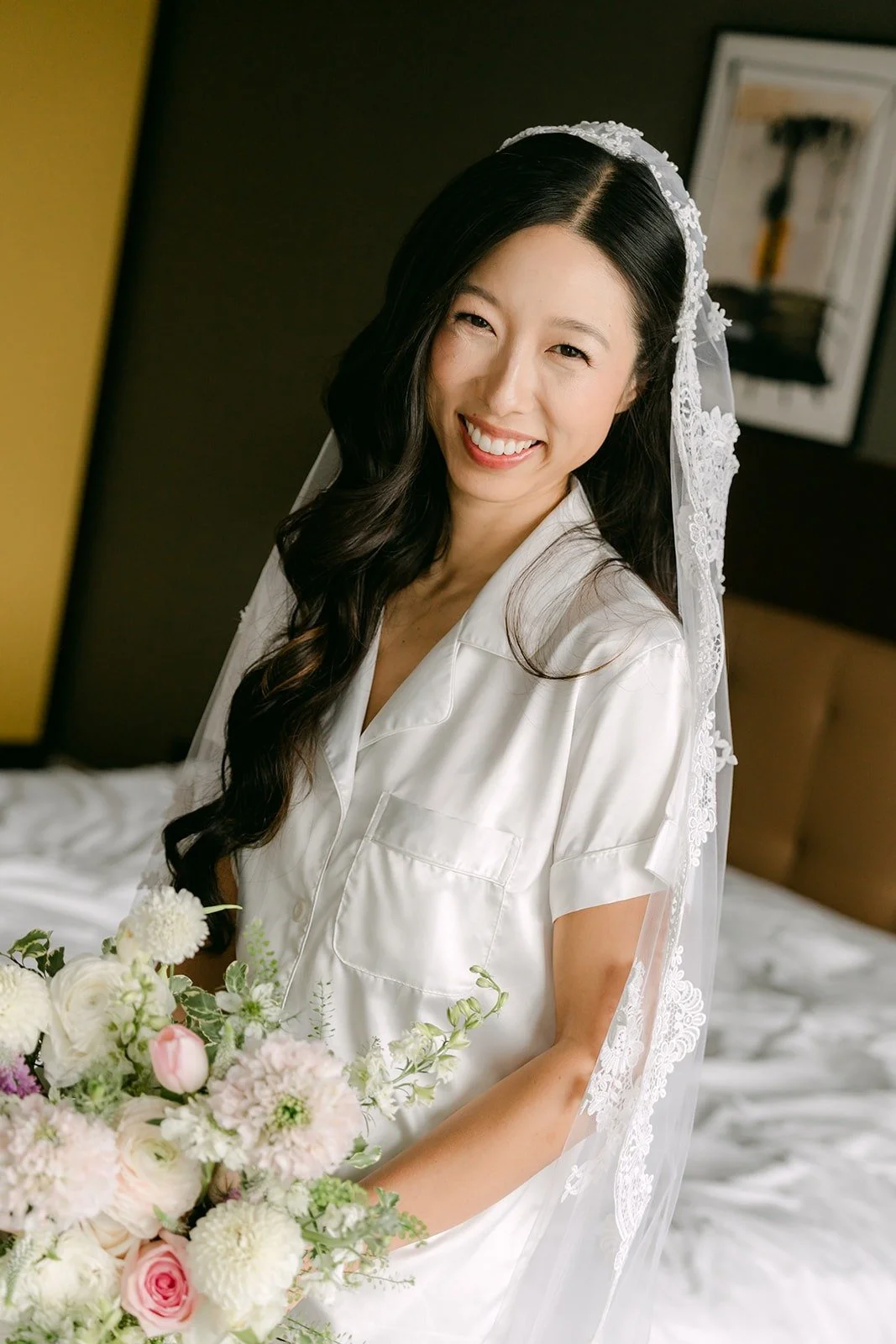 Kristine in her robe and lace veil, smiling with her bouquet