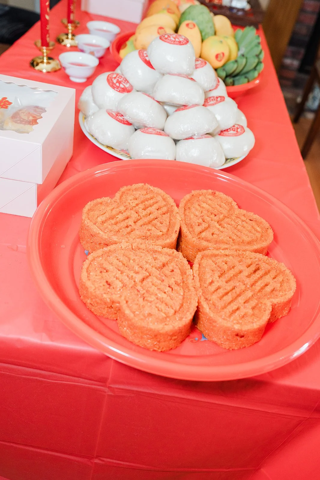 Plates of traditional pastries and sweets set out on a red tablecloth.