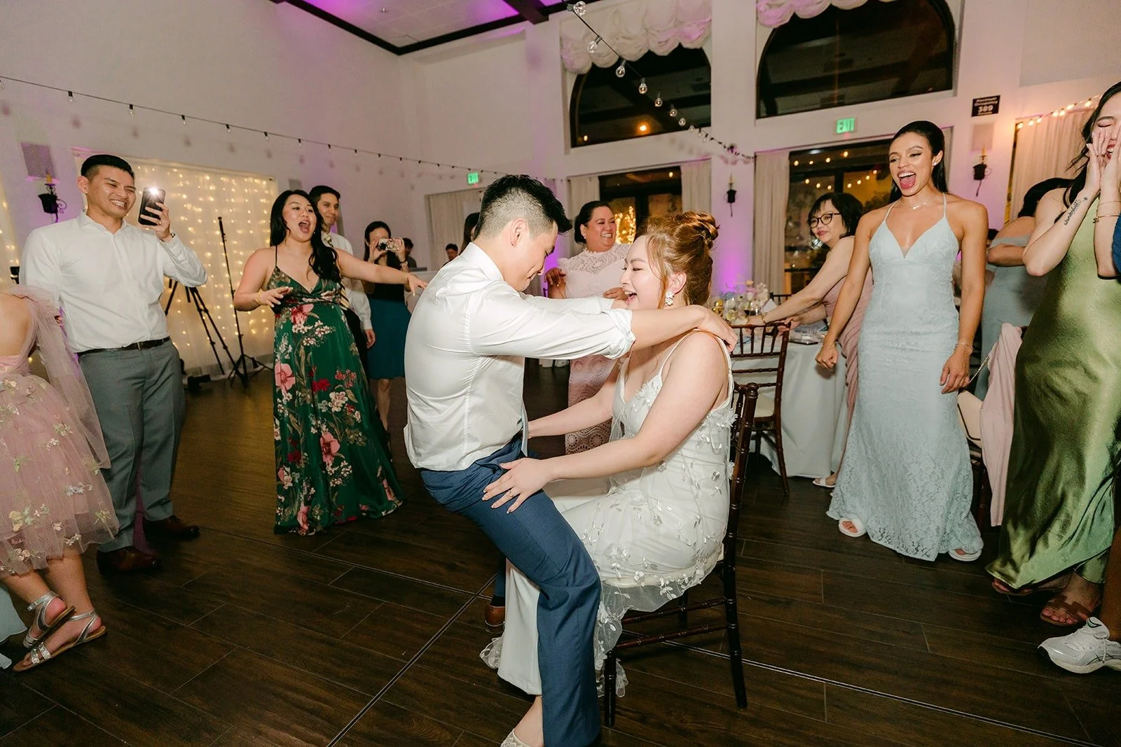 A guest dancing low as friends cheer him on