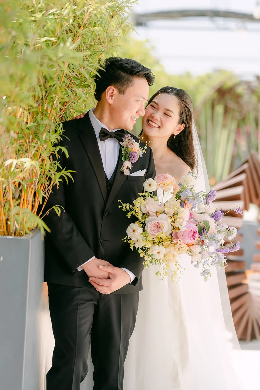 Linh and Hoan smiling at each other beside bamboo on the resort grounds