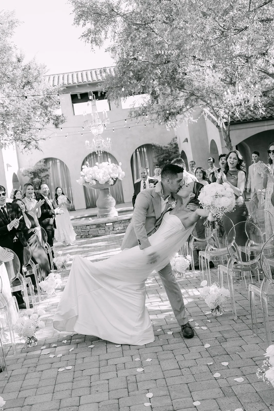 Black and white photo of the newlywed dip kiss in the courtyard