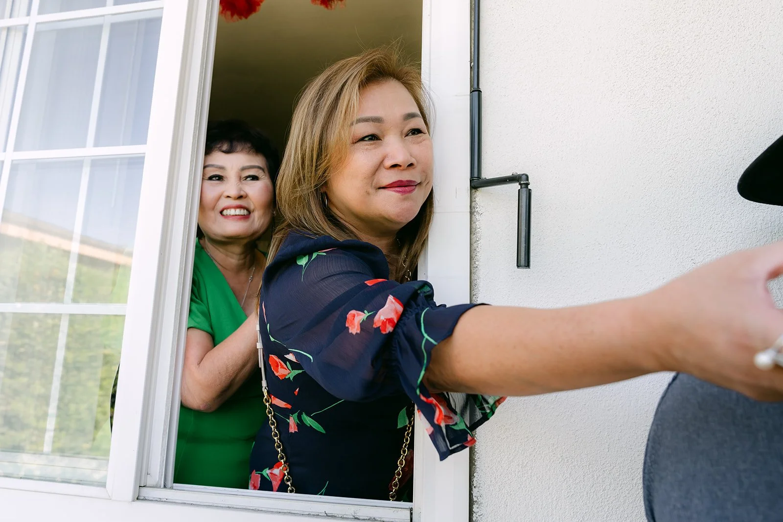An aunt reaching out the window for a red envelope during the door games.