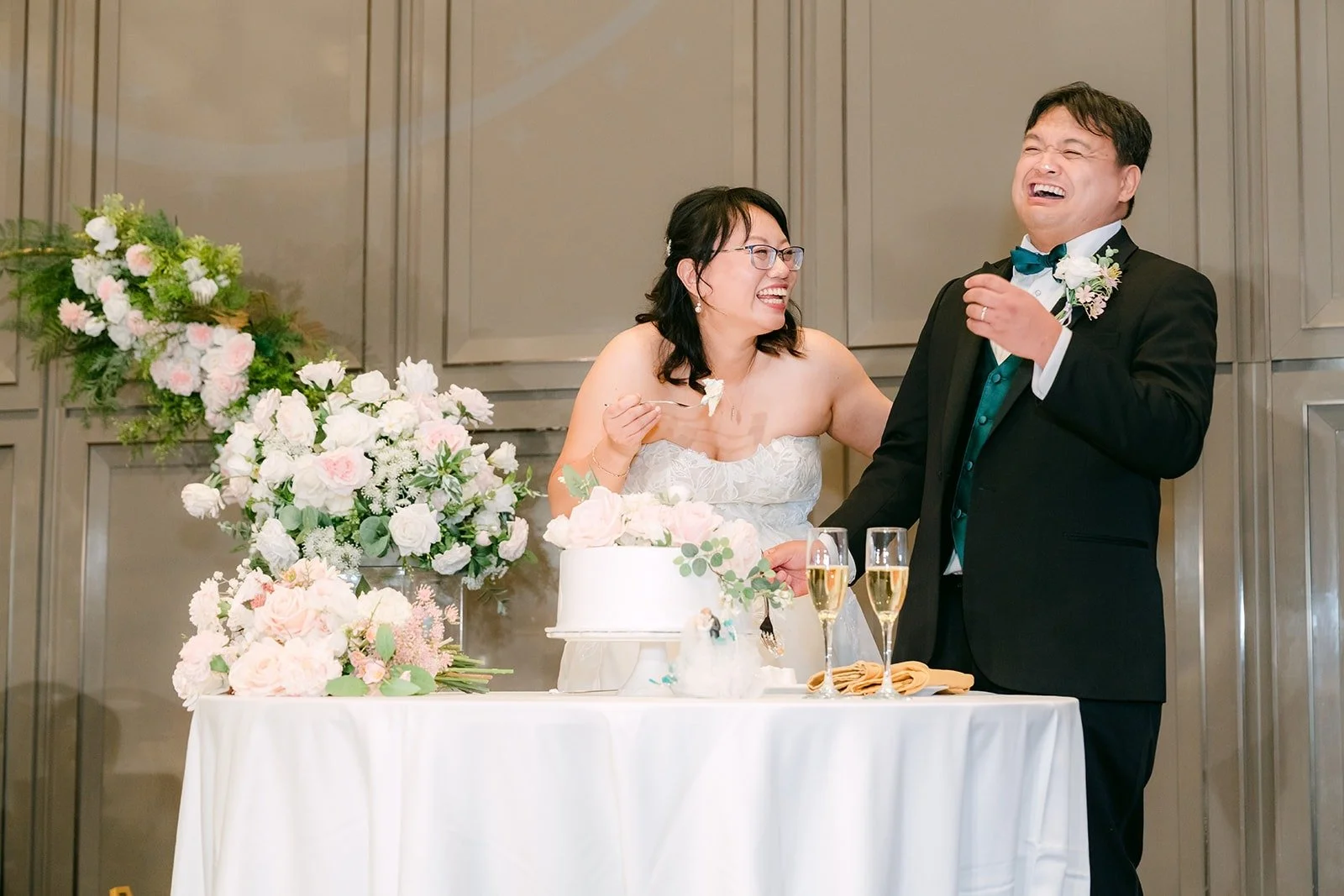 Stella and James laughing as they cut their wedding cake