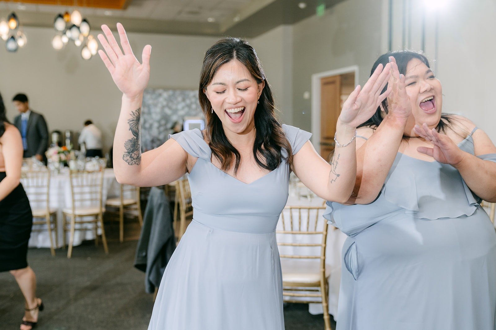 Bridesmaids in dusty blue singing along on the dance floor