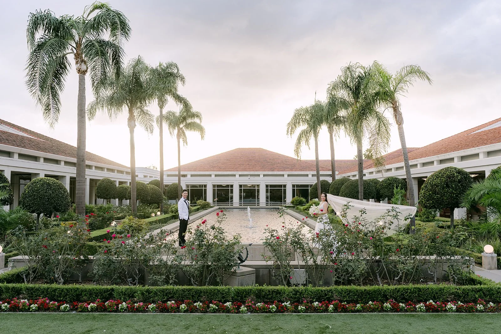 Jenny and Ryan at the reflecting pool at the Nixon Library, framed by palm trees.