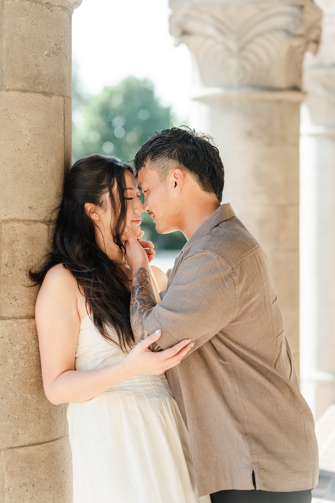 Victoria and Andrew touch foreheads beside a carved column.