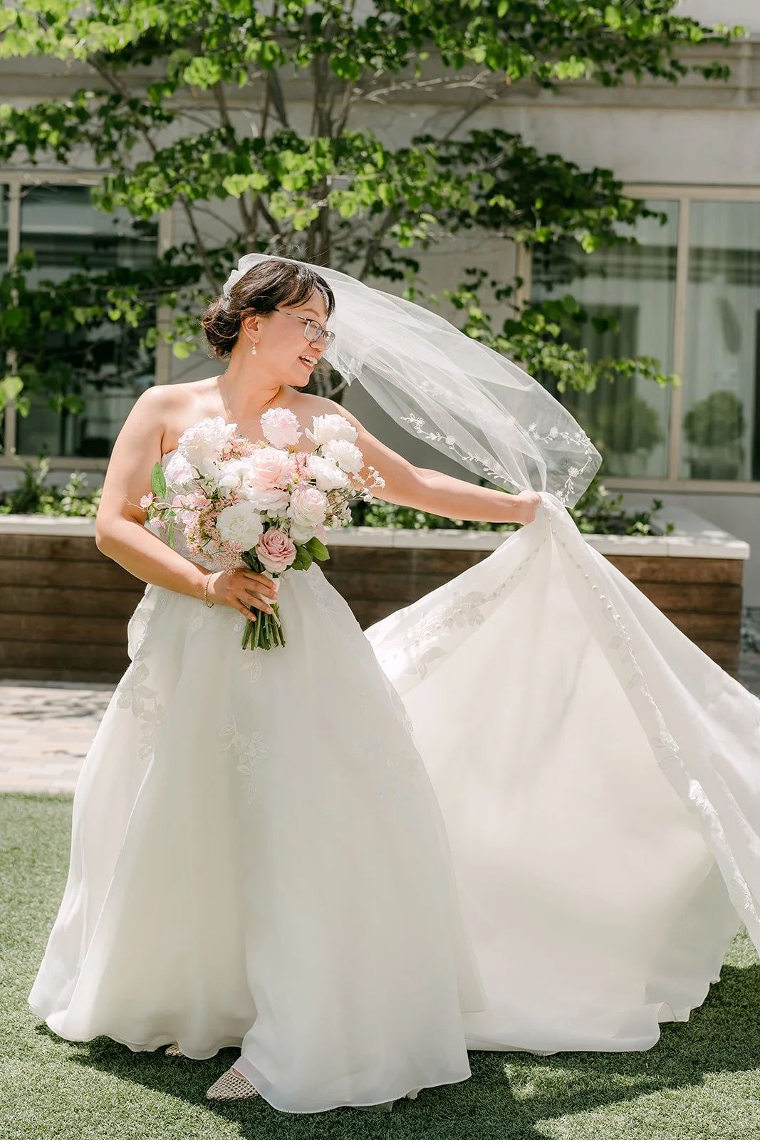 Stella lifting her veil in the breeze on the courtyard lawn