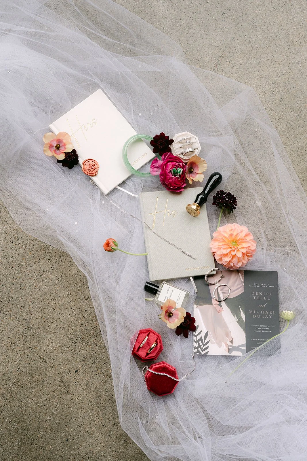 Denise and Michael's wedding flat lay on tulle with their invitation, ring boxes, perfume and blush and burgundy florals.