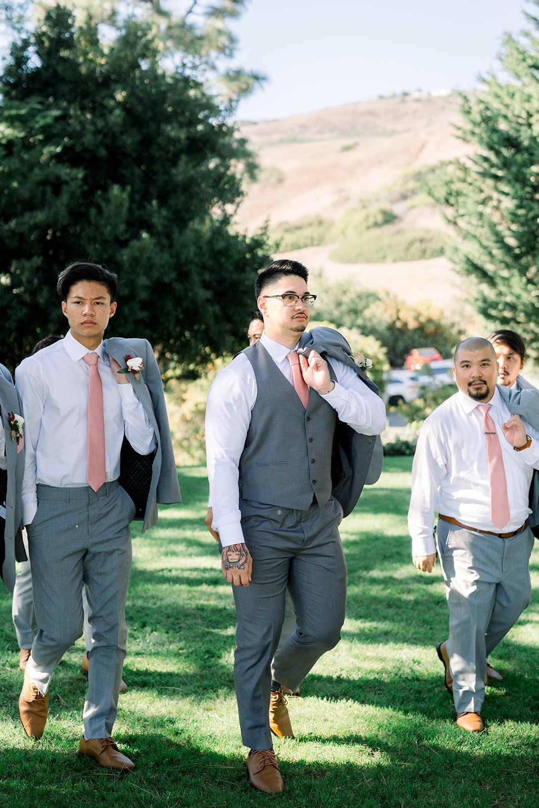 Mikey walks across the lawn with his groomsmen