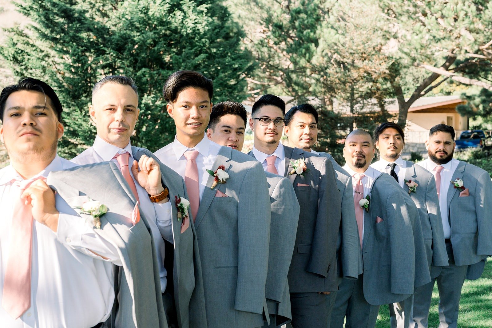 The groomsmen laughing together in grey vests and suits