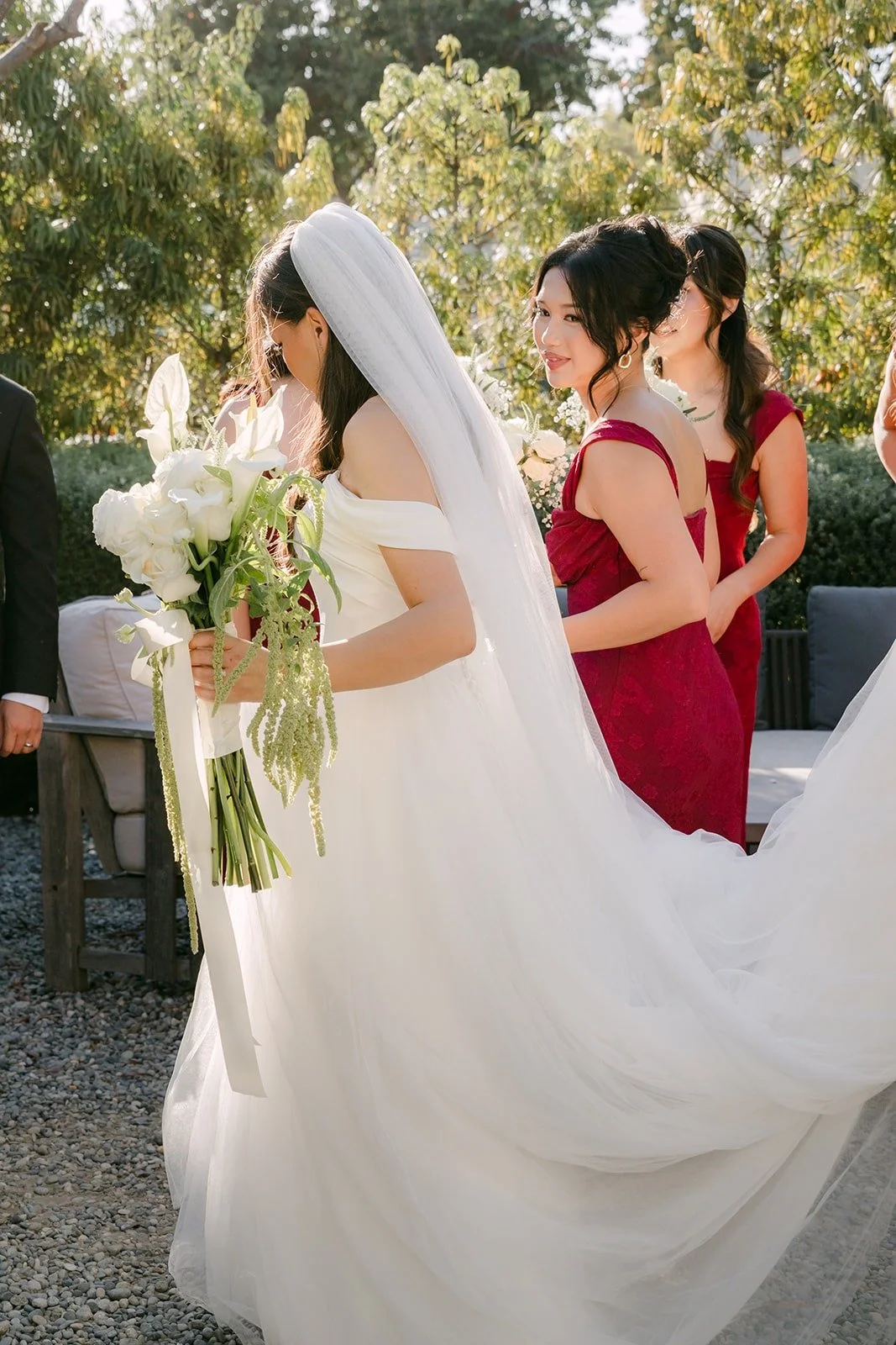 Bridesmaids fixing Jadee's veil and train in the garden