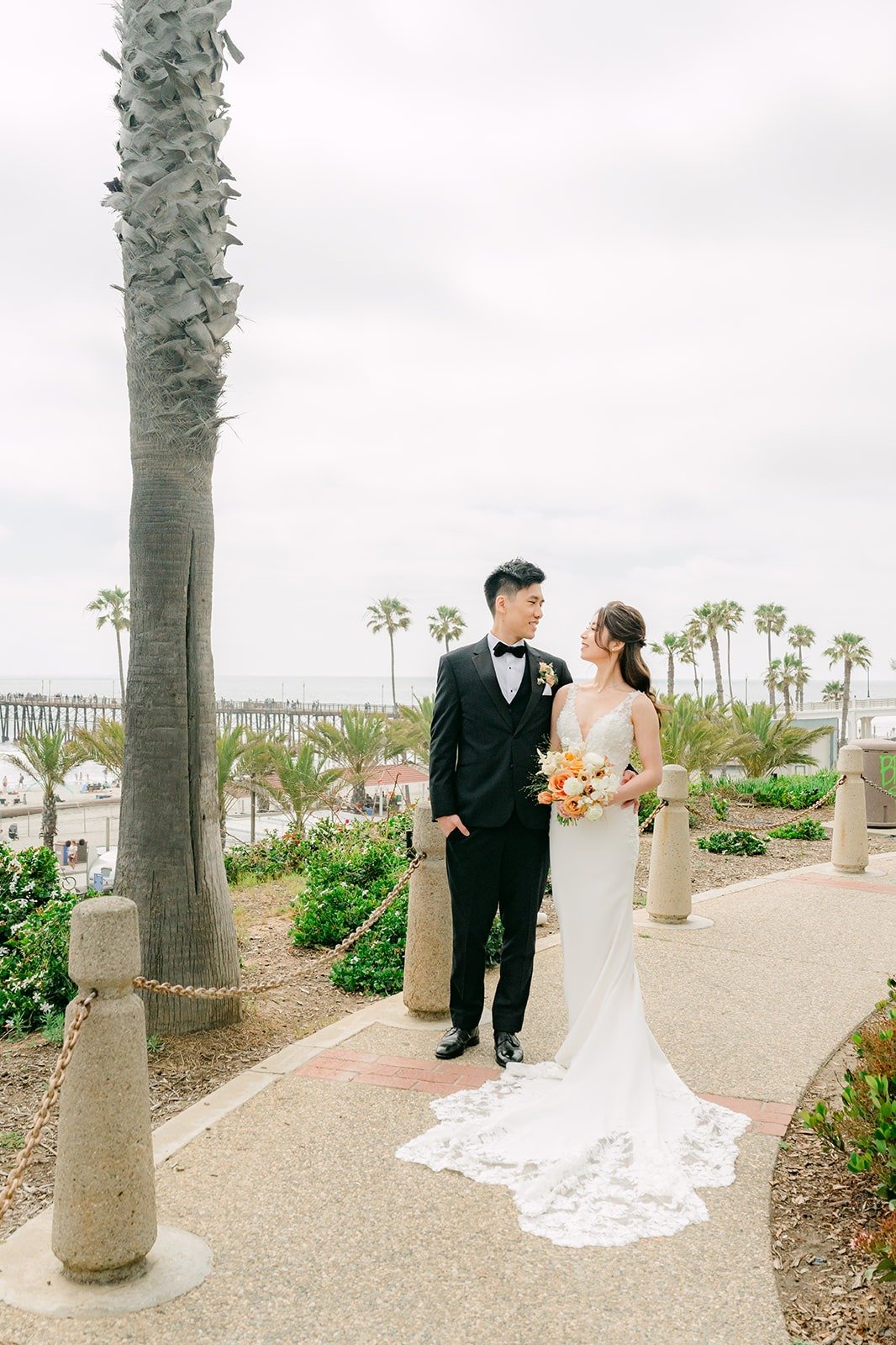 Angela and Eli on the oceanfront walkway lined with palms near the resort