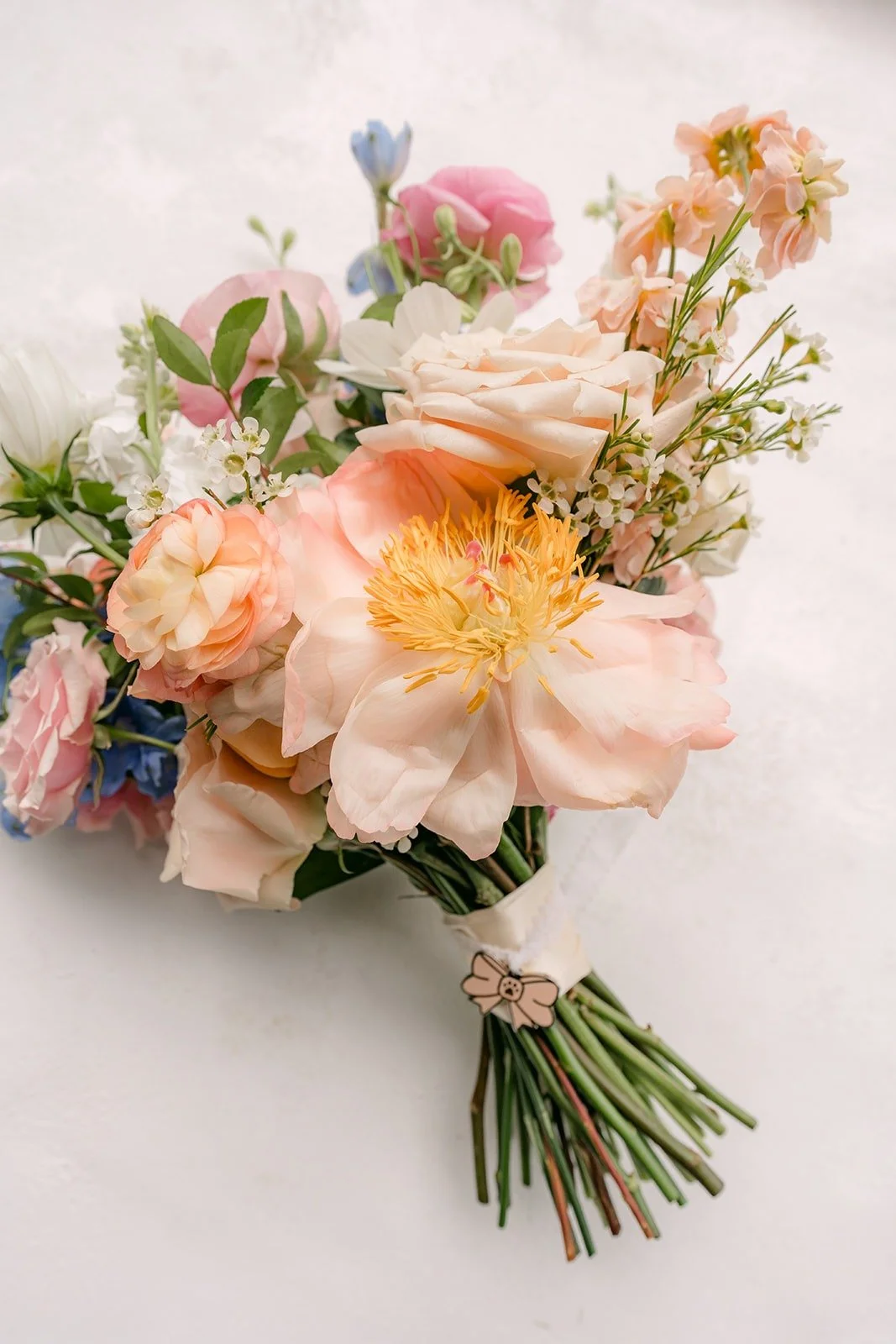 Natalie's bridal bouquet of peach, pink and blush blooms with long green stems, photographed by One and Only Production