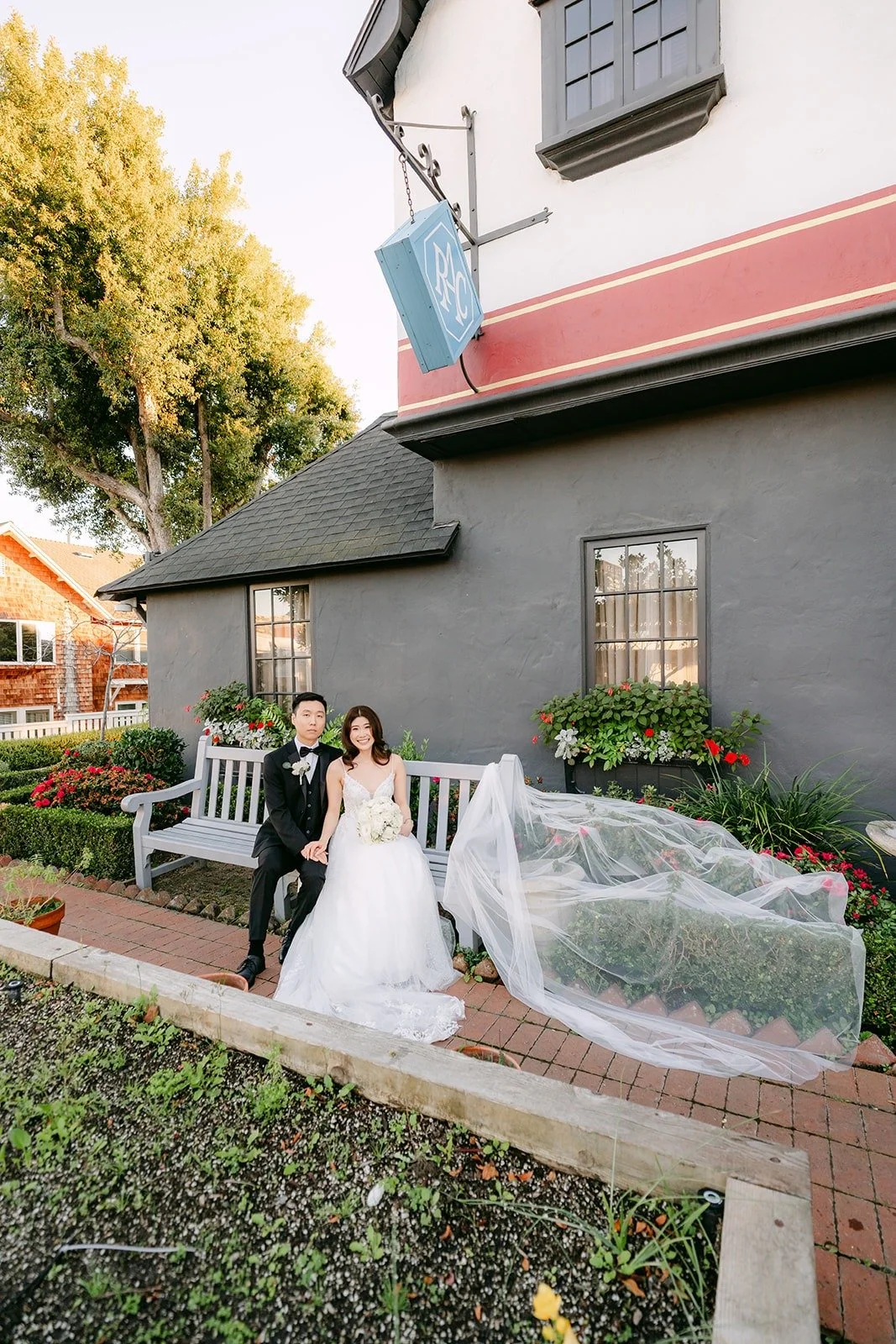 Valerie and Jason on the white bench with her veil spread on the path