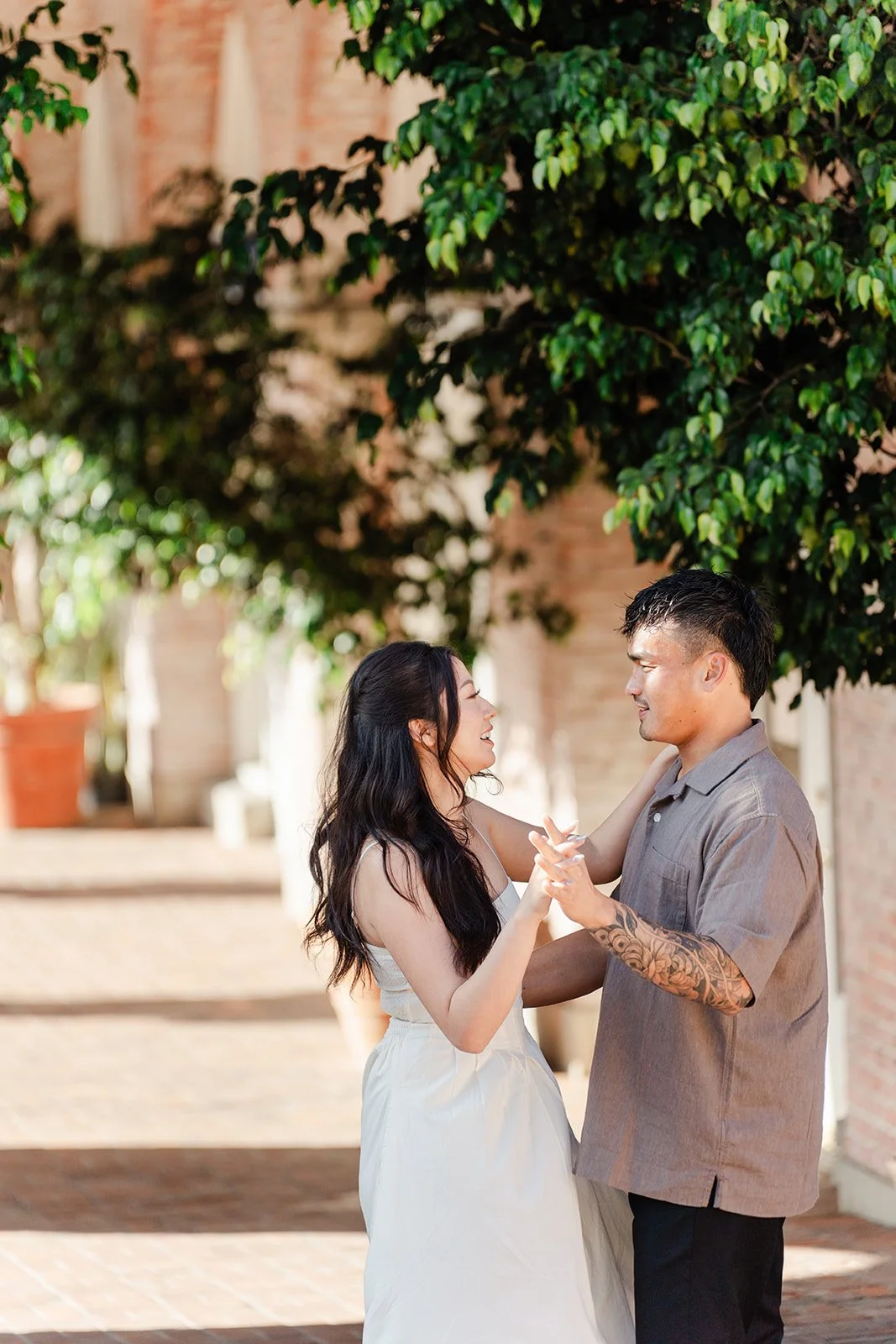 Victoria and Andrew hold hands beneath a vine-covered arch.