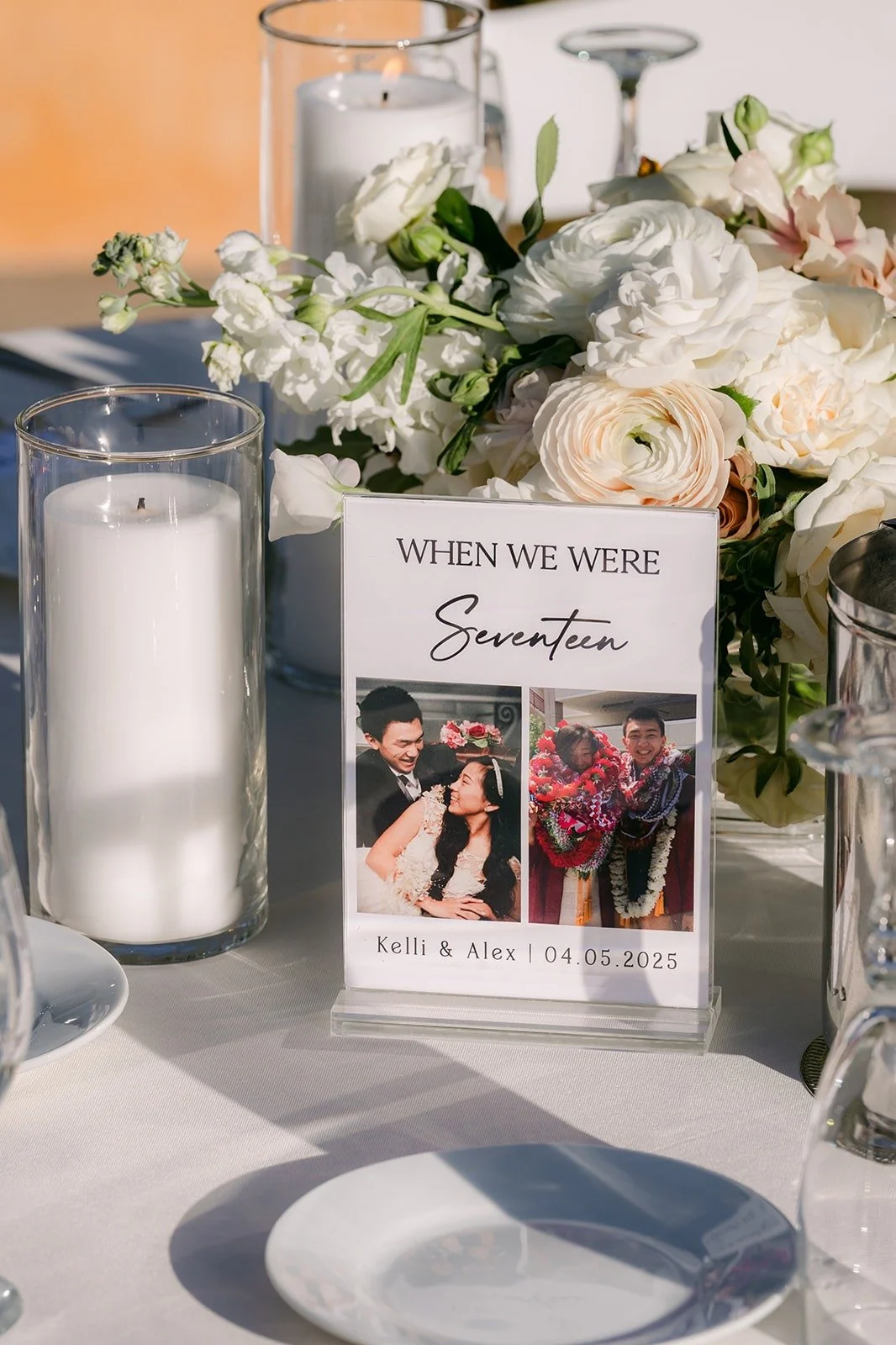 A centerpiece of ivory flowers and candles beside a framed table photo