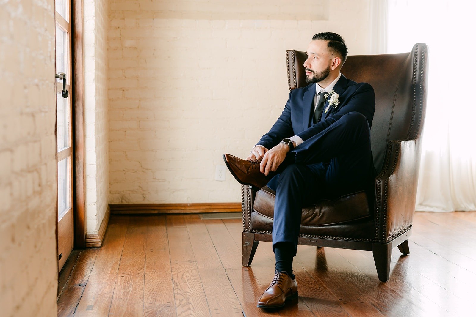 Danny seated in a leather armchair in his navy suit