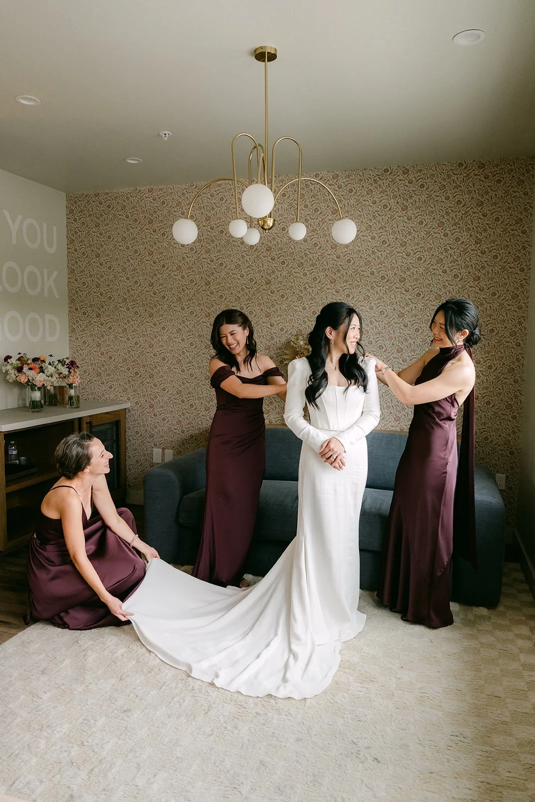 Bridesmaids in burgundy fluffing the train of Denise's gown.