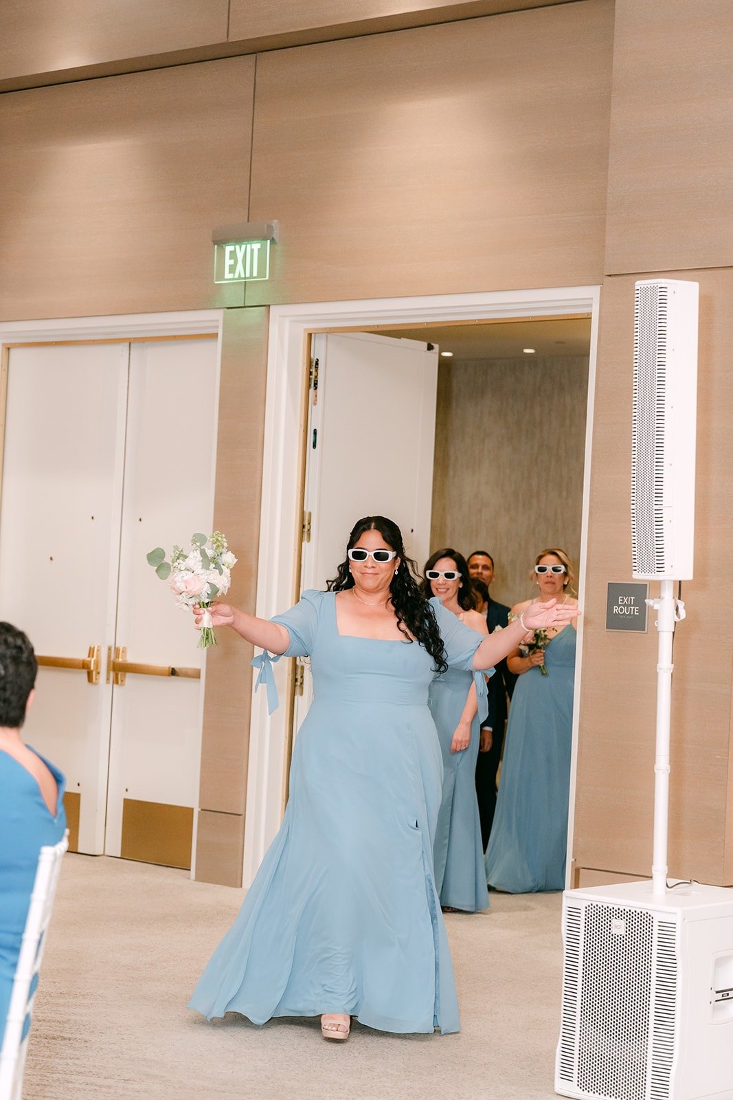 A bridesmaid in light blue dances into the Carousel Ballroom for the grand entrance