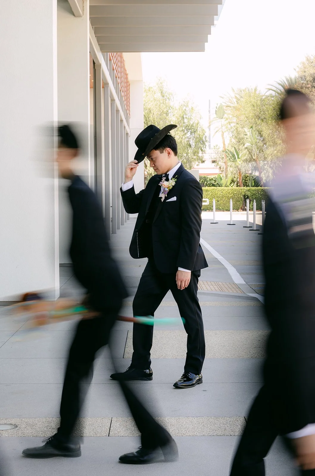 Groom tipping a cowboy hat as his groomsmen blur past