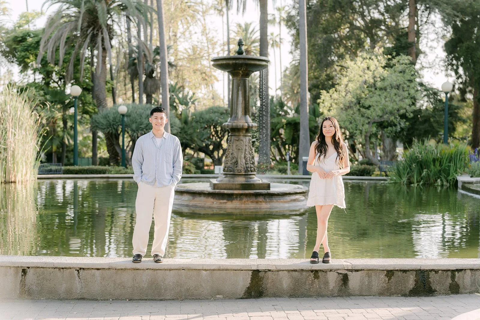 Jadee and Richard stand together beside the fountain pond.