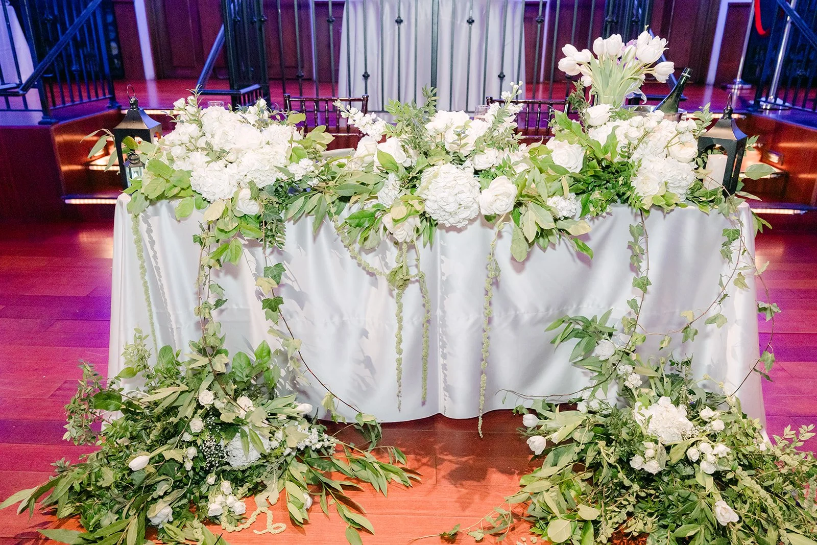 Sweetheart table draped in white florals and greenery