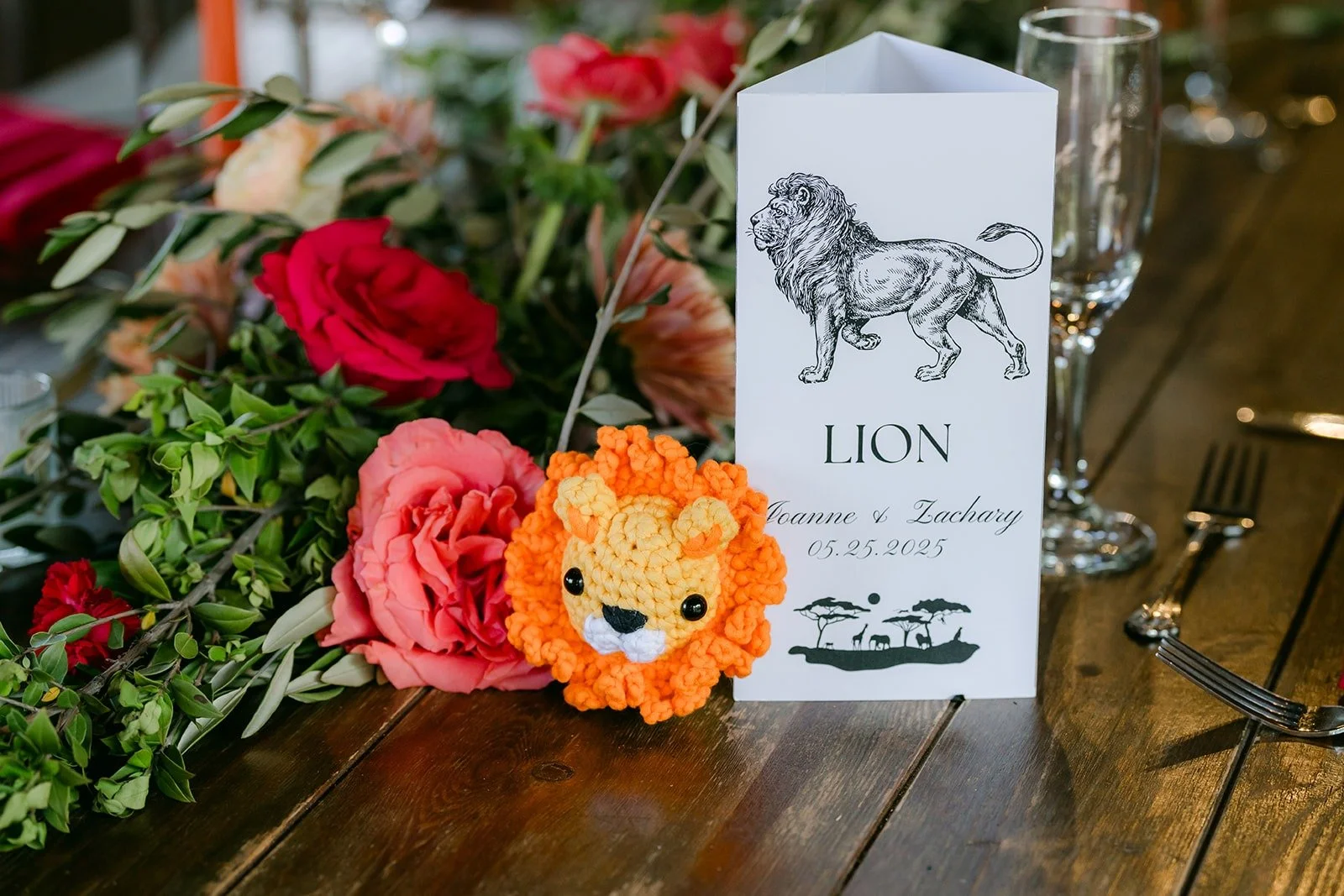 A table card named Lion with a lion cutout among the red and pink flowers