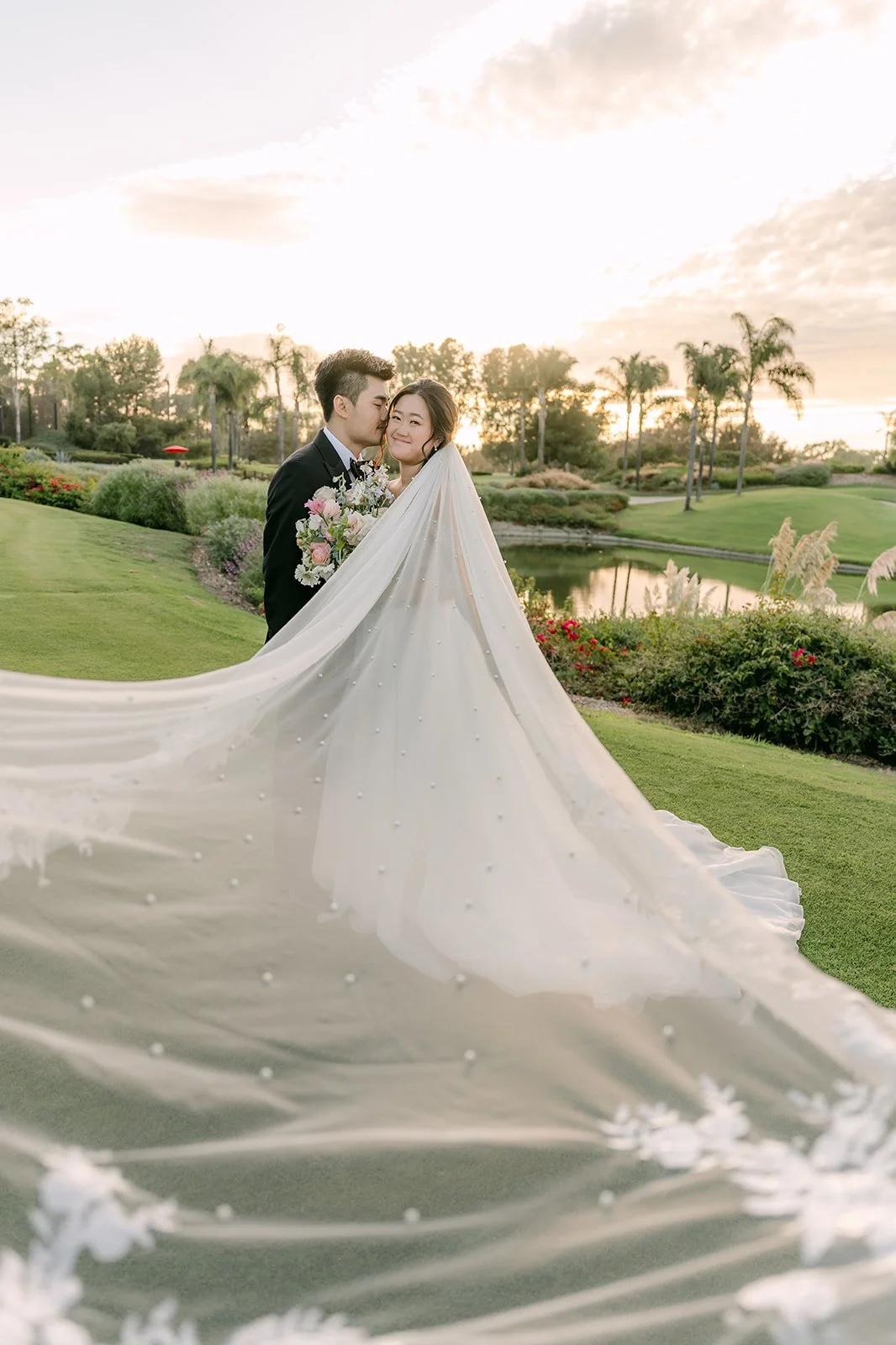 Jessica's long veil flowing across the lawn at golden hour