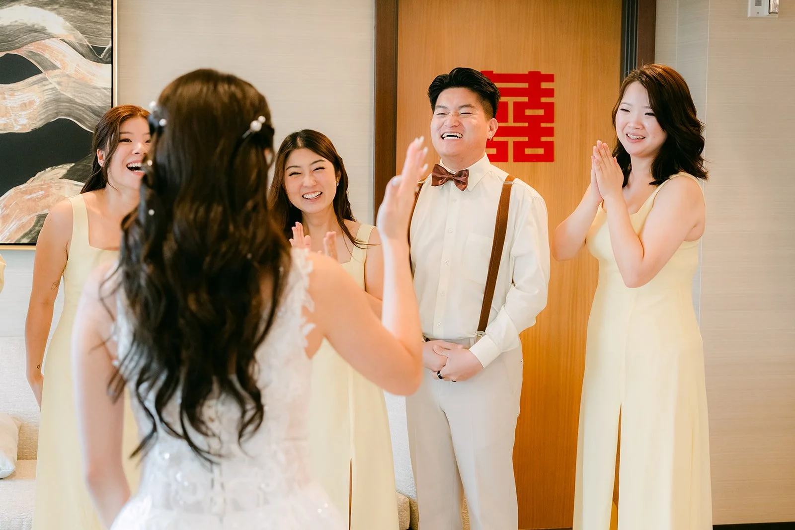 Bridesmaids clapping and cheering for Jenny, a red double happiness sign on the door.