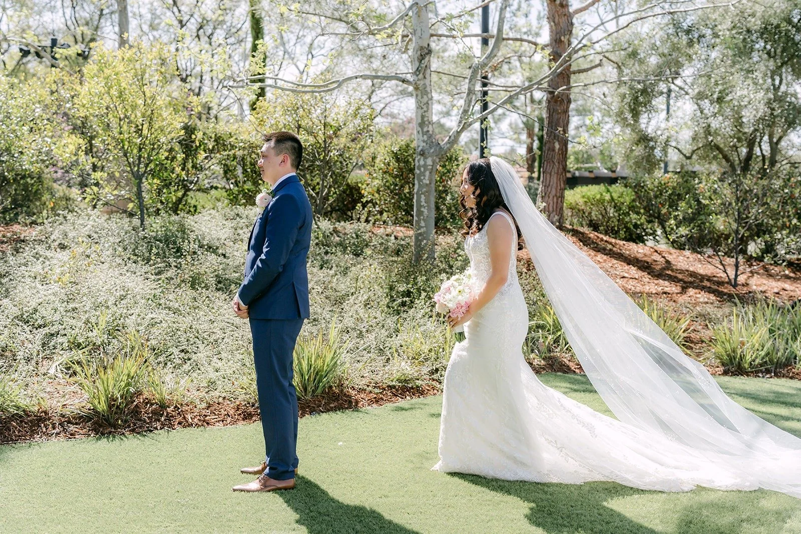 Alex waiting with his back turned as Kelli walks up behind him on the lawn