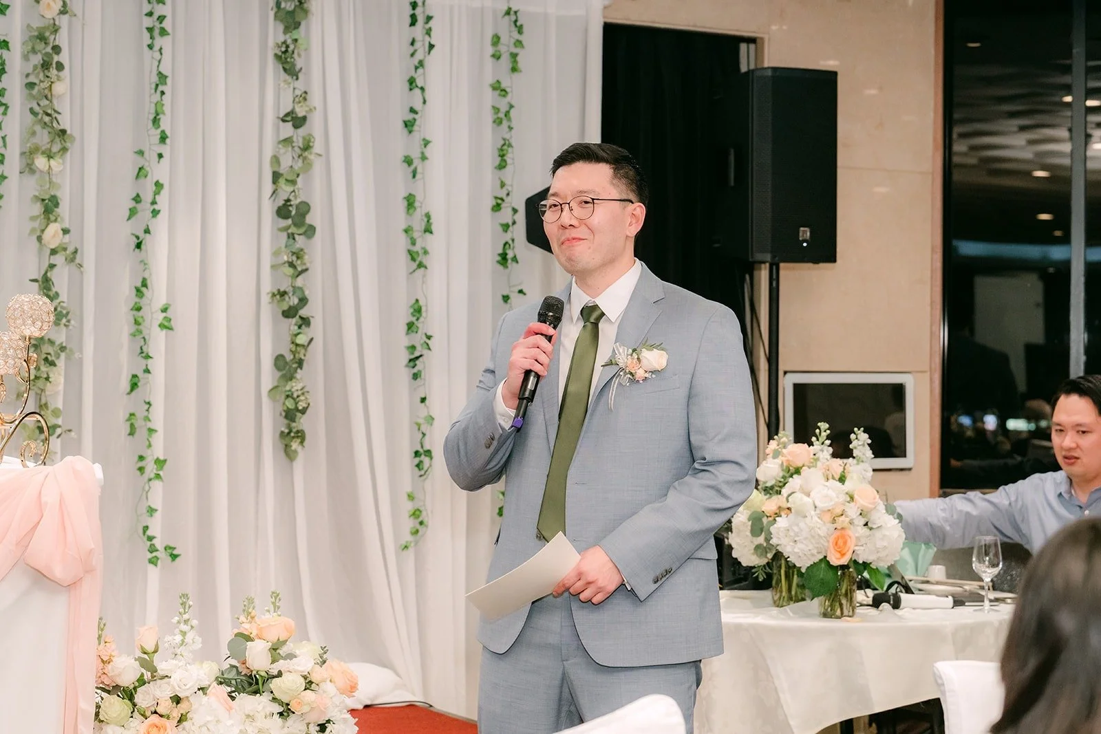A groomsman in a gray suit gives a toast