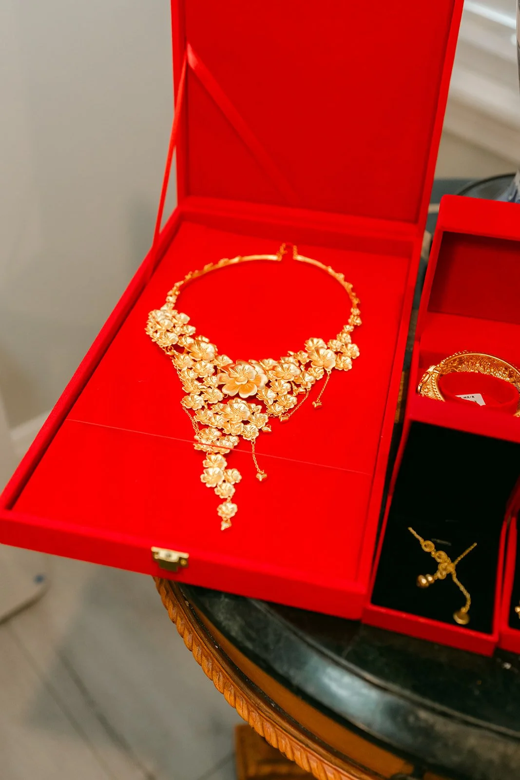 A gold necklace and earrings displayed in a red jewelry box.